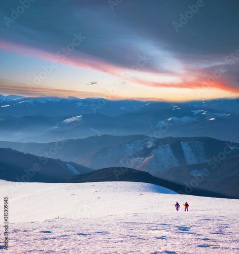 Obraz na płótnie Mystical landscape with two travelers in the winter mountains at sunset w salonie