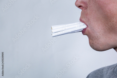 A person's face filmed in a profile with lots of cigarettes in his mouth. photo