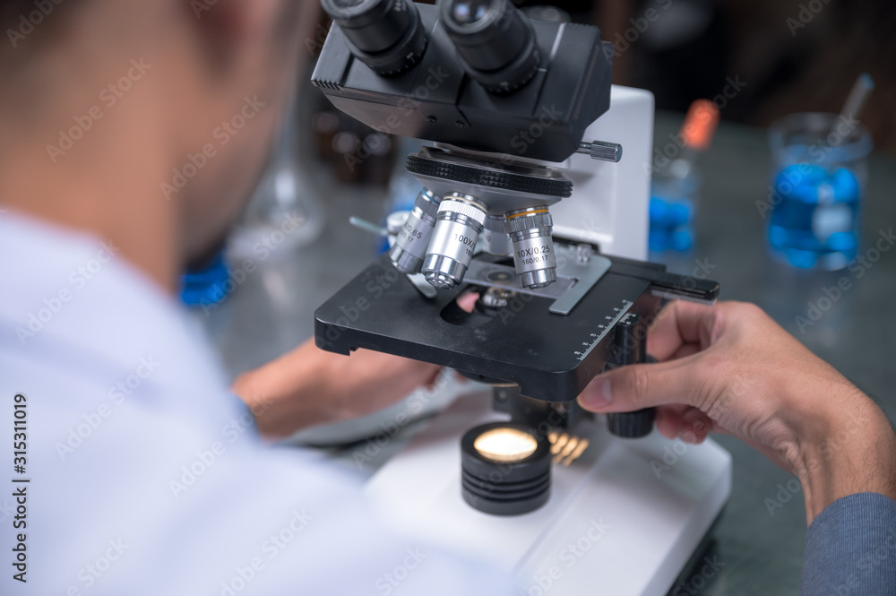 Young scientist looking through a microscope in a laboratory. Young scientist doing some research. Young scientist looking through a microscope in a laboratory. Young scientist doing some research.