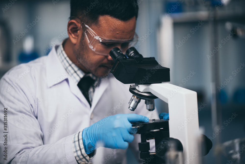 Young scientist working with a microscope in a laboratory. Young scientist doing some research. Young scientist working with a microscope in a laboratory. Young scientist doing some research.