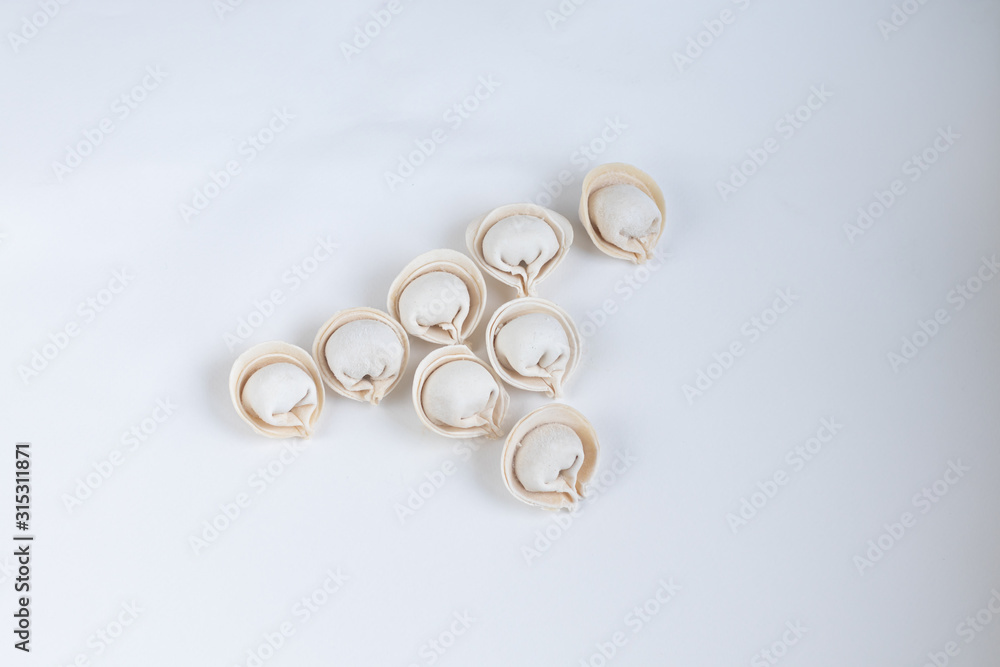 Several raw, frozen dumplings on a light background. View from above. Several raw, frozen dumplings on a light background. View from above.