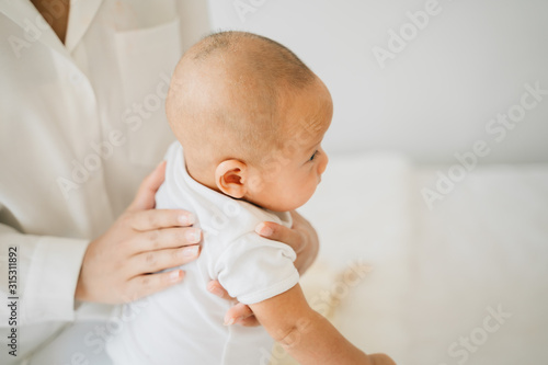 Tablou pe pânză From above of mom patting adorable newborn son massaging back of Asian baby on b