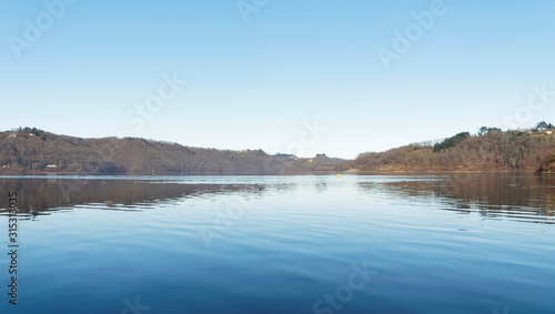 Vue sur les eaux calmes du grand lac de Bort-les-Orgues et ses berges au bord de la Commune de Lanobre