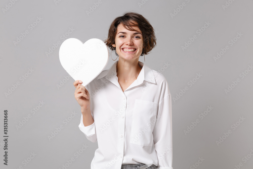 Funny attractive young business woman in white shirt posing isolated on  grey wall background studio portrait. Like blogging social network concept.  Mock up copy space. Hold white blank empty heart. Stock Photo |