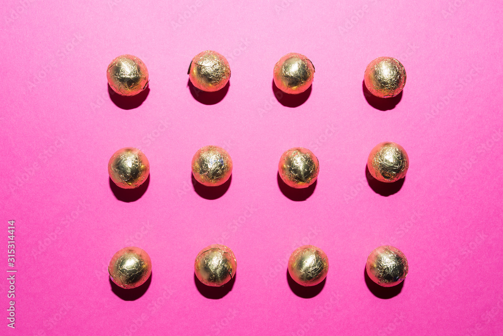 Chocolates in a multi-colored foil on a pink background Chocolates in a multi-colored foil on a pink background