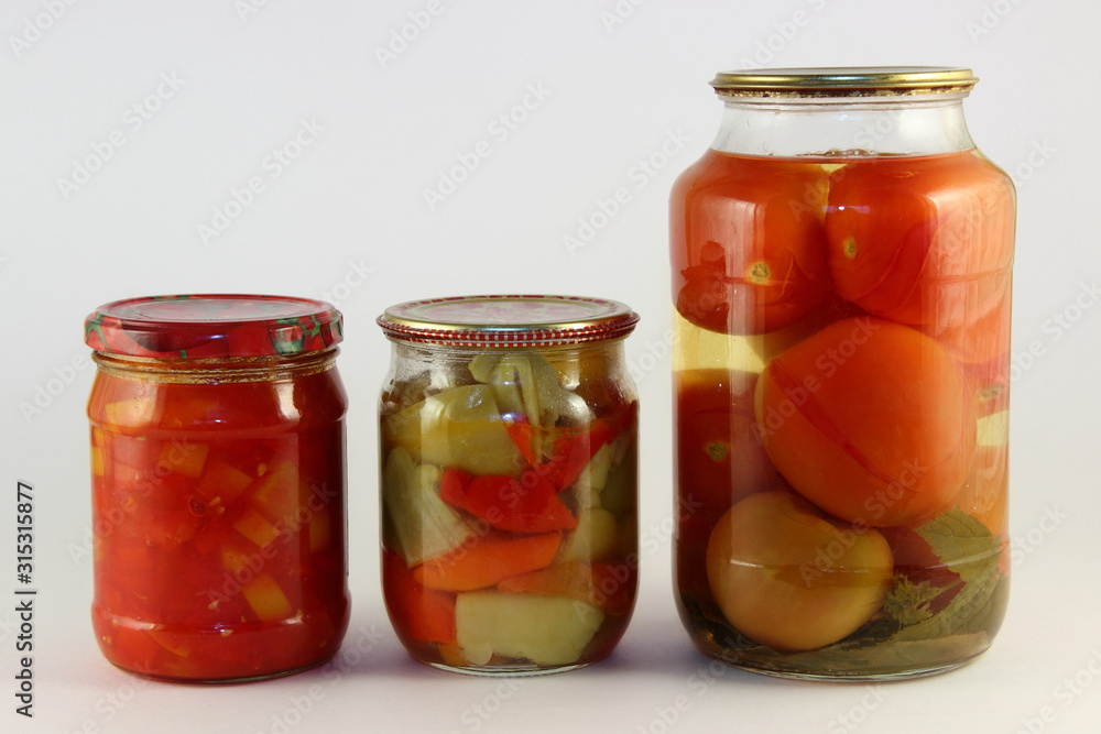 Tasty canned vegetables mix, pickled paprika, and potatoes in a glass jars with metal caps on white background, ecological homemade pickles Tasty canned vegetables mix, pickled paprika, and potatoes in a glass jars with metal caps on white background, ecological homemade pickles