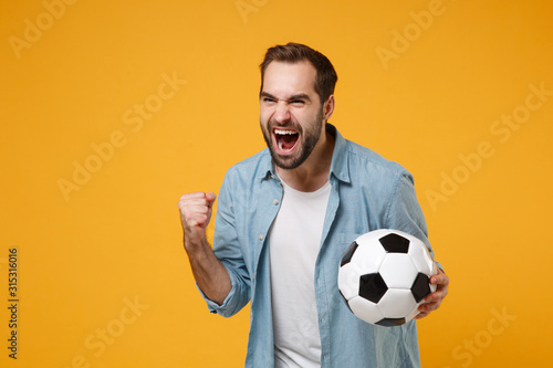 Fotografie Joyful happy young man in blue shirt posing isolated on yellow orange background