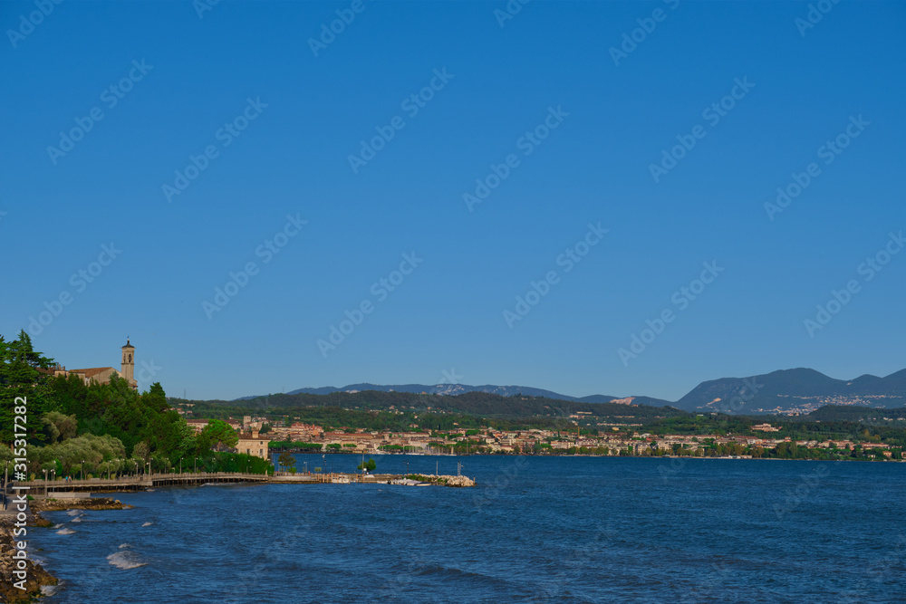 Panoramic view of the city of Rivoltella del Garda, Italy. Lake Garda, blue sky, church on a hill lake view