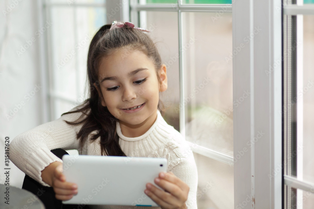 Adorable little child girl using a tablet. Electronic communication Adorable little child girl using a tablet. Electronic communication