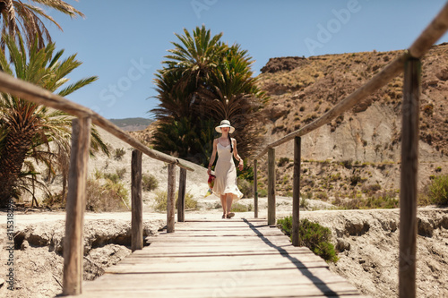 Woman wearing dress walking on a wooden bridge in the desert