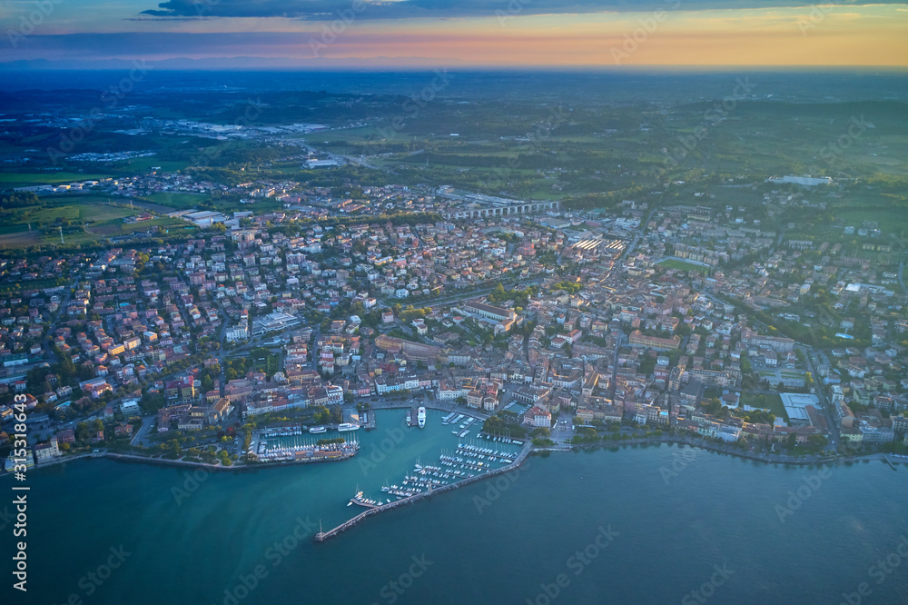 Aerial view of the city center of Desenzano del Garda, Italy. The main lighthouse of the city, boat parking in the city center. The ship leaves the city