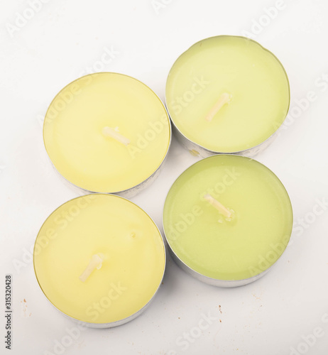 Several small multicolored candles in aluminum casings on a white background. Close up.