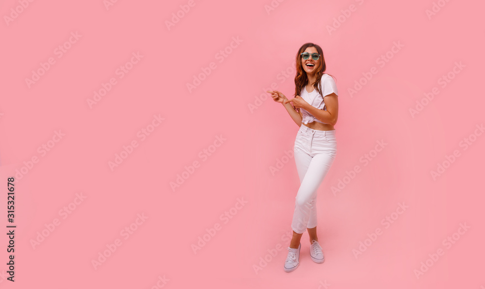 Image of happy young lady standing isolated over pink background. Looking camera pointing.Photo of happy young woman standing isolated over pink wall background, showing copyspace. Image of happy young lady standing isolated over pink background. Looking camera pointing.Photo of happy young woman standing isolated over pink wall background, showing copyspace.