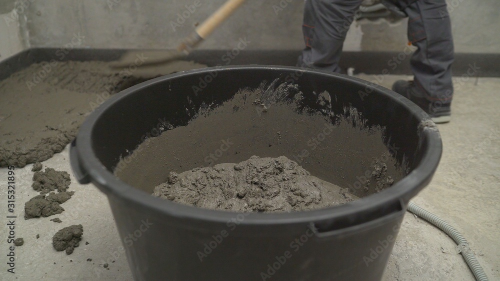 Black bucket with mortar for filling the floor. Bucket with mortar at the construction site. Black bucket with mortar for filling the floor. Bucket with mortar at the construction site.