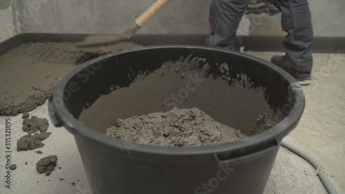 Black bucket with mortar for filling the floor. Bucket with mortar at the construction site.