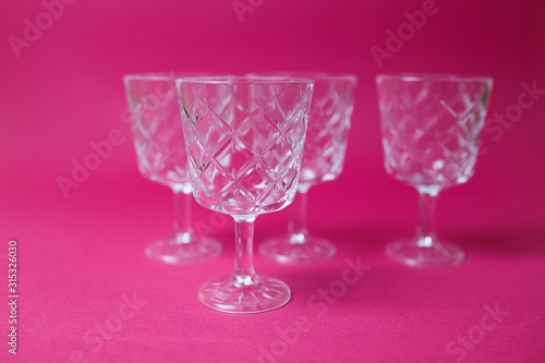 Four wine glasses on pink background with copy space.