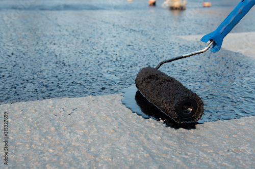 Worker applies bitumen mastic on the foundation