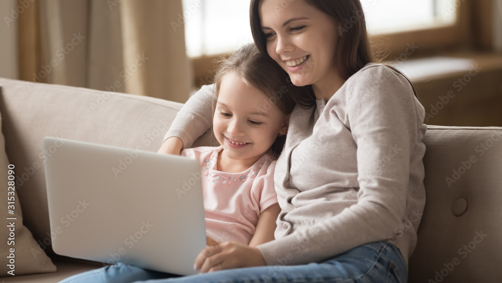 Happy mother and little daughter using laptop together at home Happy mother and little daughter using laptop together at home
