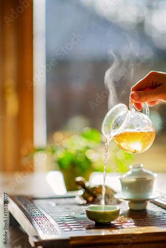 Fotografija Tea brewing process, tea ceremony, a cup of freshly brewed green oolong tea, warm soft light