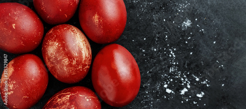 Greeting card with easter eggs painted in monochrome red shiny dye style on black background with white crumbs, egg shell with white stains, scuffs, scratches. handmade Flat lay with copy space