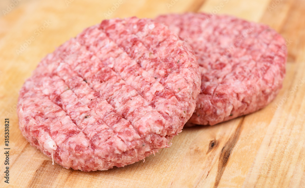 Soft focus. Raw pink beef cutlet isolated on a cutting board. Soft focus. Raw pink beef cutlet isolated on a cutting board.