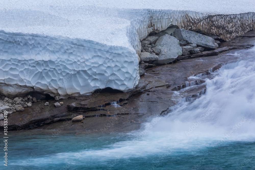 Blue river water and snow in norwegian tundra