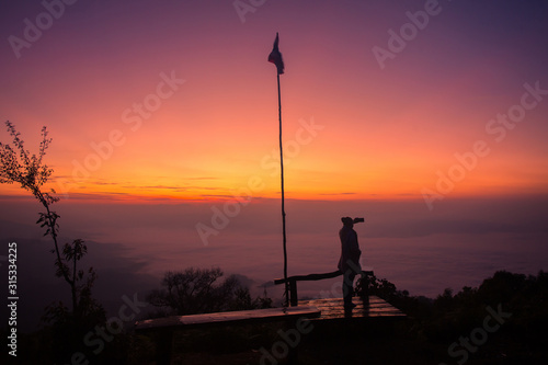 Silhouette of a girl in front of the sunset on the hill.