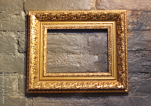 decorative gold colored picture frame on a brickstone wall