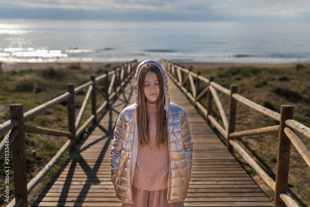 teen on the beach with hood on wooden walkway teen on the beach with hood on wooden walkway