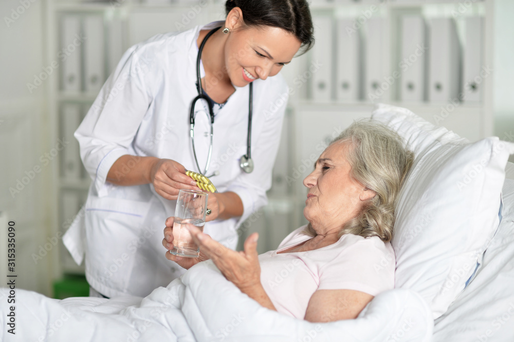 Fototapeta premium Senior woman in hospital with caring doctor