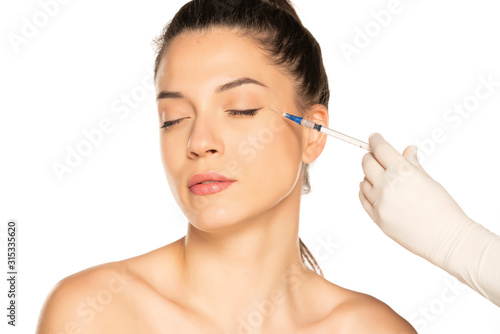 Portrait of a young beautiful woman on a face filler injection procedure on white background