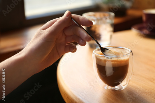 Woman with aromatic coffee at table in cafe, closeup