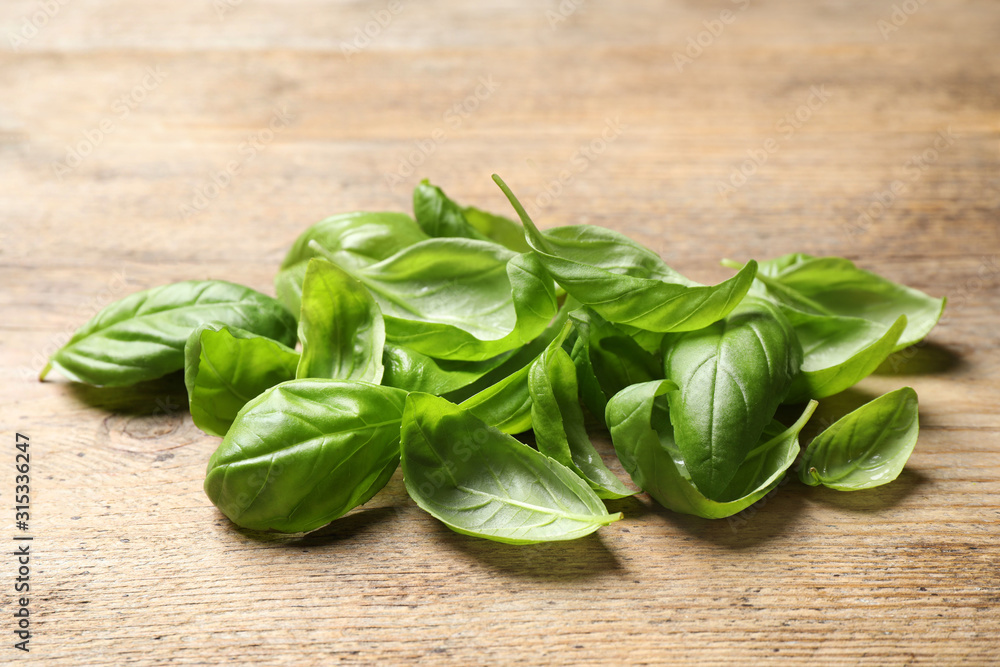 Fresh green basil leaves on wooden table Fresh green basil leaves on wooden table