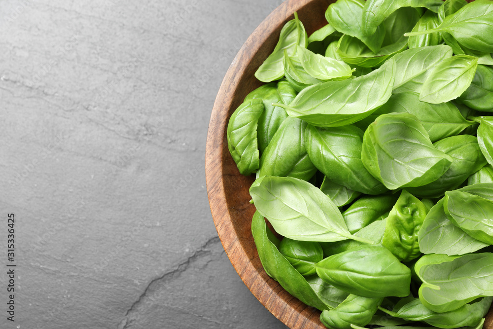 Fresh basil leaves on grey table, top view Fresh basil leaves on grey table, top view