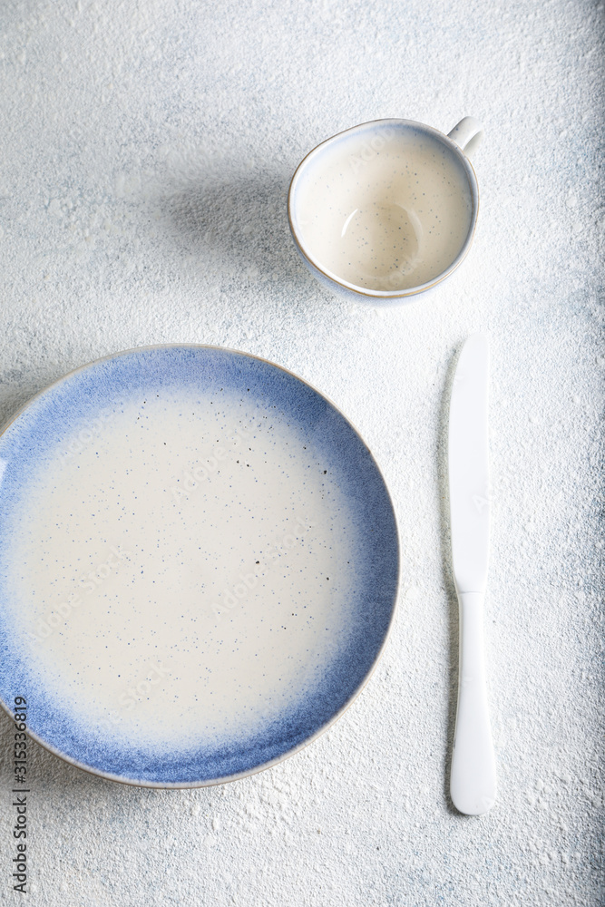 White with blue empty plate with cutlery on marble table. Marble background. Copyspace. Top view. White with blue empty plate with cutlery on marble table. Marble background. Copyspace. Top view.