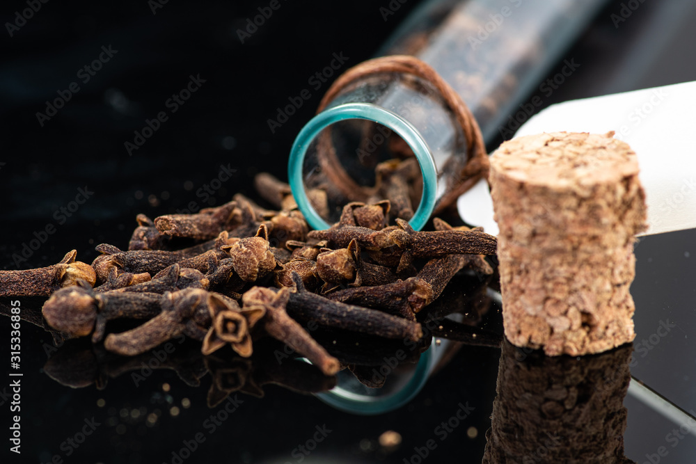 dried clove spice next to test tube and cork