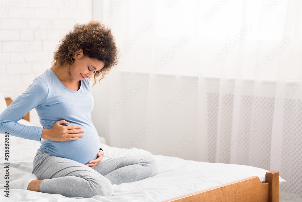 Pretty afro pregnant woman keeping hands on belly Pretty afro pregnant woman keeping hands on belly