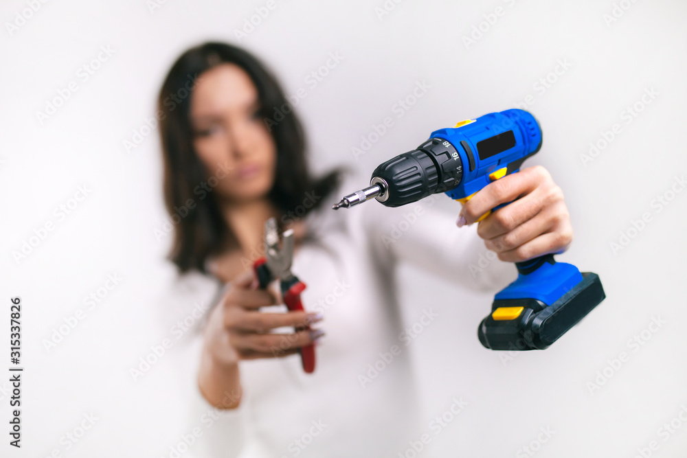 the girl in the hands holds a screwdriver and pliers in the foreground the girl in the hands holds a screwdriver and pliers in the foreground