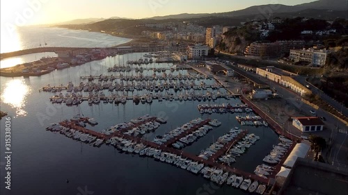 Dramatic sunset over the mediterranean sea in El Maresme Coast. Aerial ultra high definition footage of Arenys de Mar harbor and city at dawn. photo