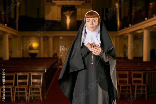 nun in church praying with rosary