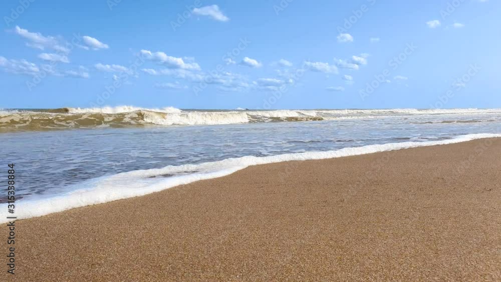 Golden sandy beach and waves splashing and making foam on the beach on sunny day. Slow motion 4k video Golden sandy beach and waves splashing and making foam on the beach on sunny day. Slow motion 4k video