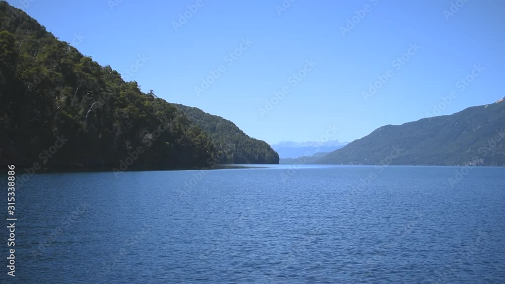 Calm lake surface and rocky coast with dense trees. Slow motion 4k nature concept footage