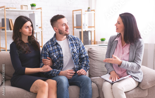 Millennial spouses talking with psychotherapist at office