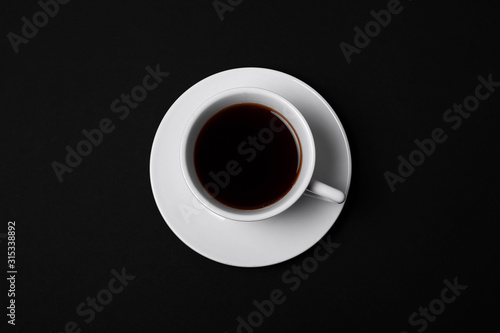 white cup of coffee on black background top view