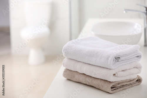 Stack of fresh towels on countertop in bathroom. Space for text