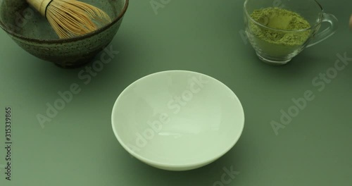 Blending green matcha tea powder in hot water with bamboo whisk to make green matcha tea latte