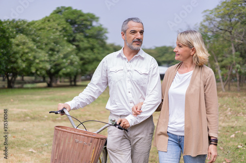 Couple elderly relaxing at park walking with bike and talking together in morning. The concept of good health and relax © sorrapongs