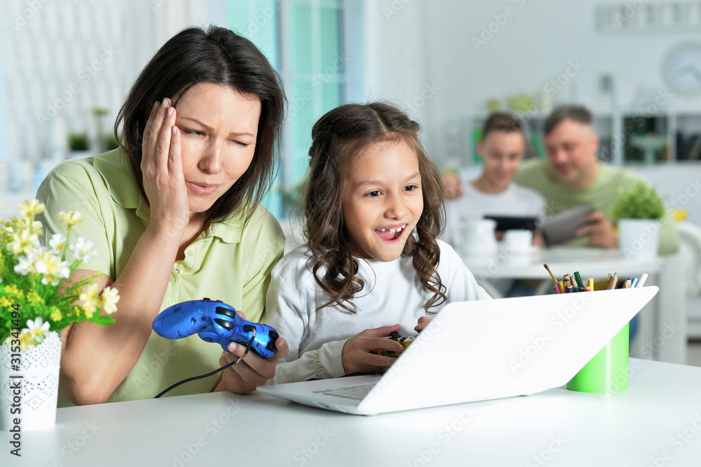Mother and daughter using laptop together playing game