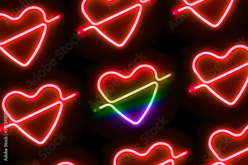 Pattern of red neon led light hearts with one heart colored rainbow - lgbt Valentine’s Day