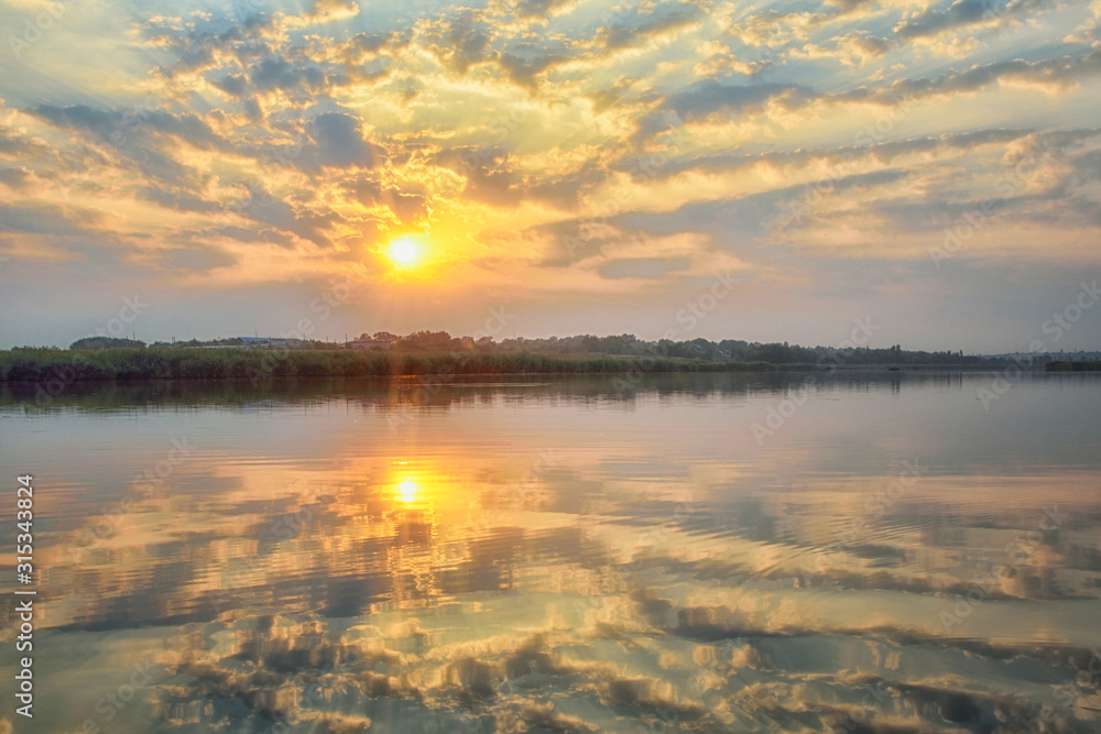 Beautiful panorama of the river landscape. Reflection of the sky and the sun in the water.